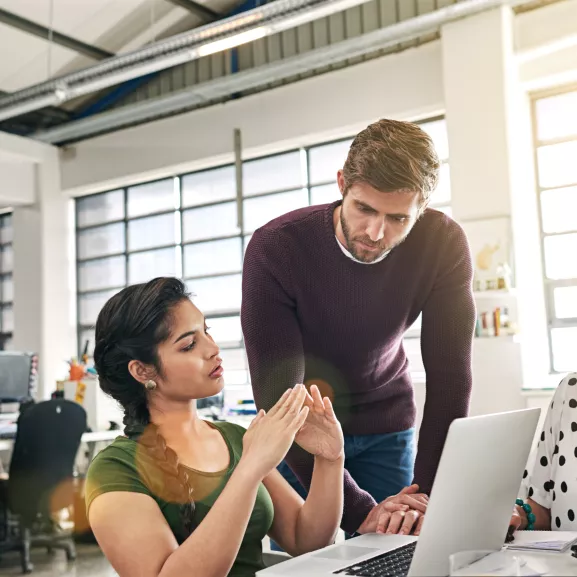 man looking at a womans work on a laptop