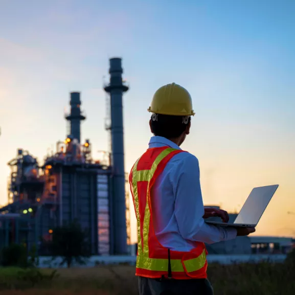 A service engineer is working at electric power plant with laptop.