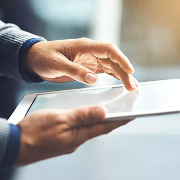 A person holding a tablet computer with their hand.