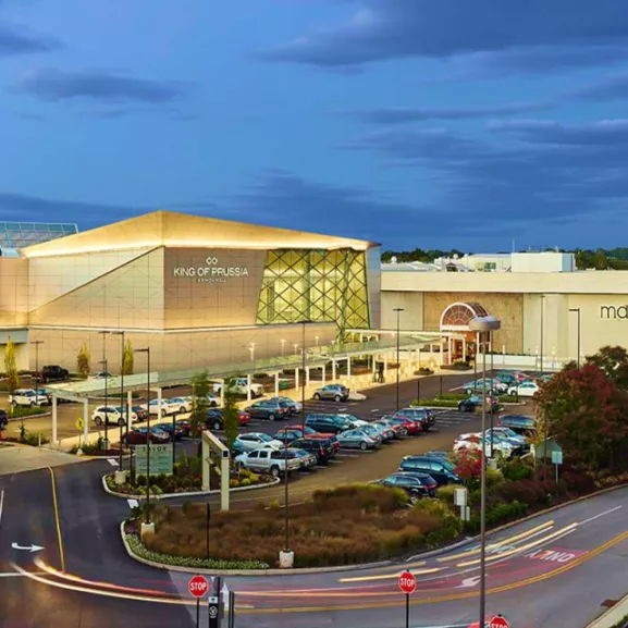 The mall at night with cars passing by.