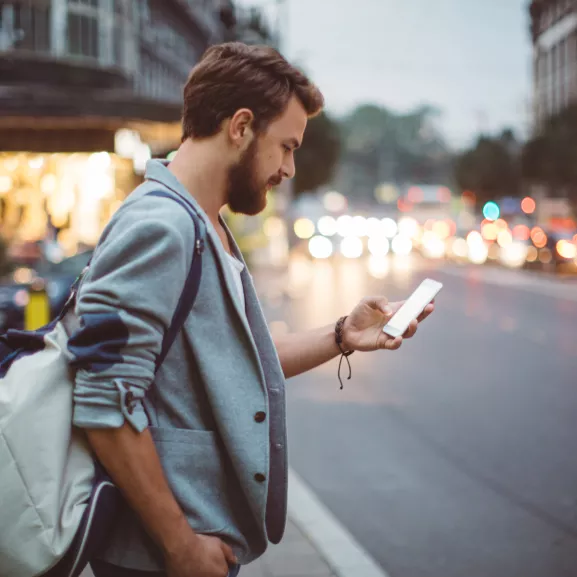 man looking at his cell phone next to a road