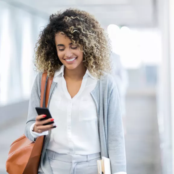 A woman, smiling and looking down at her phone.