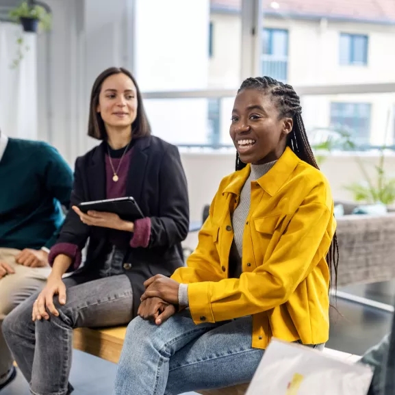 woman in yellow jacket talking to a group with other people